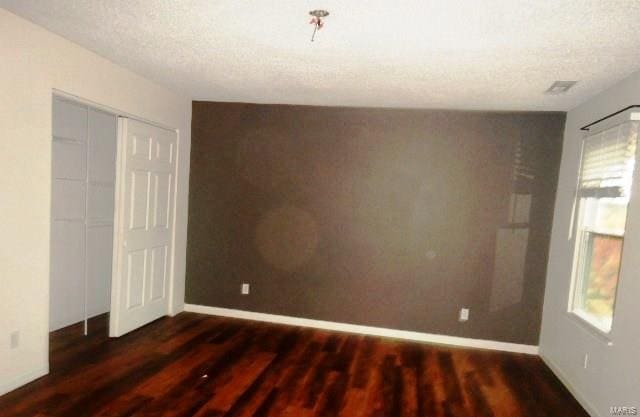 empty room with a textured ceiling and dark wood-type flooring