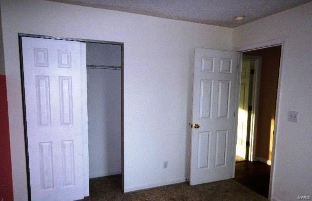 unfurnished bedroom featuring dark carpet and a closet