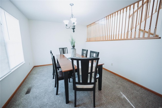 carpeted dining space with an inviting chandelier