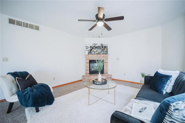 carpeted living room with a brick fireplace and ceiling fan