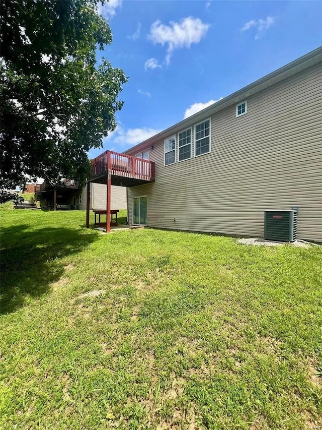 back of property featuring a wooden deck, cooling unit, and a yard