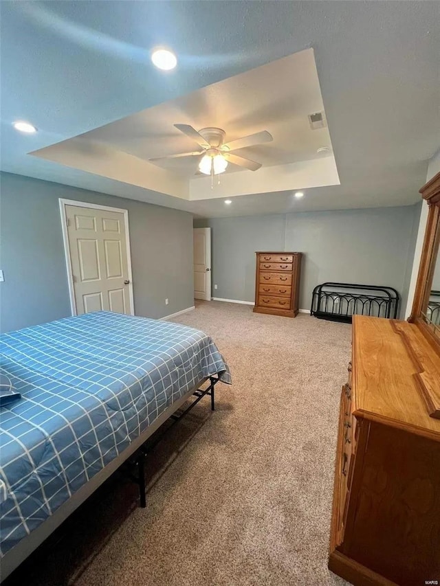 bedroom featuring carpet floors, ceiling fan, and a raised ceiling