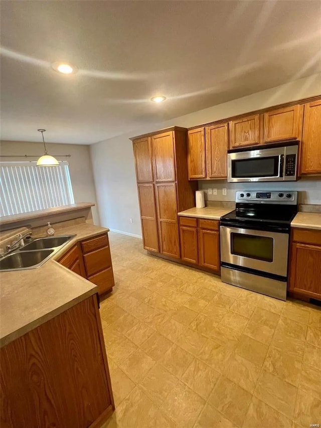 kitchen with sink, appliances with stainless steel finishes, and decorative light fixtures