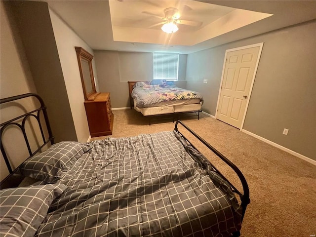 bedroom with carpet floors, a tray ceiling, and ceiling fan