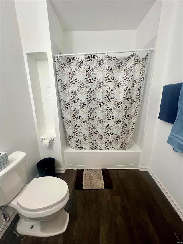 bathroom featuring toilet, shower / bath combination with curtain, and wood-type flooring