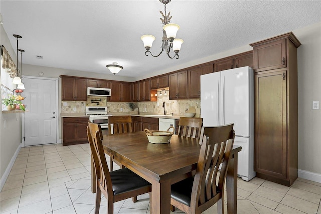 tiled dining space with a notable chandelier, a textured ceiling, and sink