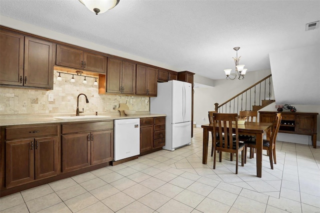 kitchen with white appliances, sink, hanging light fixtures, light tile patterned floors, and an inviting chandelier