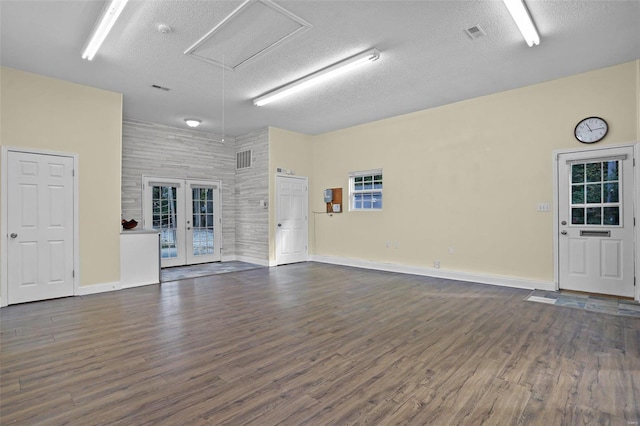 spare room featuring french doors, a textured ceiling, a high ceiling, and dark hardwood / wood-style flooring