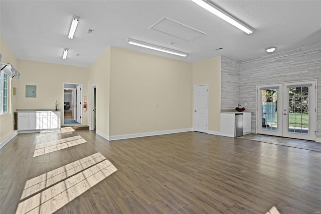 unfurnished living room with a towering ceiling, french doors, and dark wood-type flooring