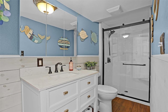 bathroom with vanity, toilet, a shower with shower door, and hardwood / wood-style floors