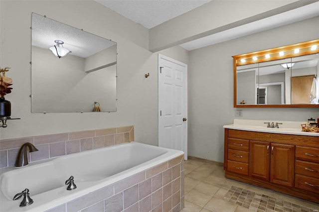 bathroom with vanity, a textured ceiling, tile patterned flooring, and tiled bath