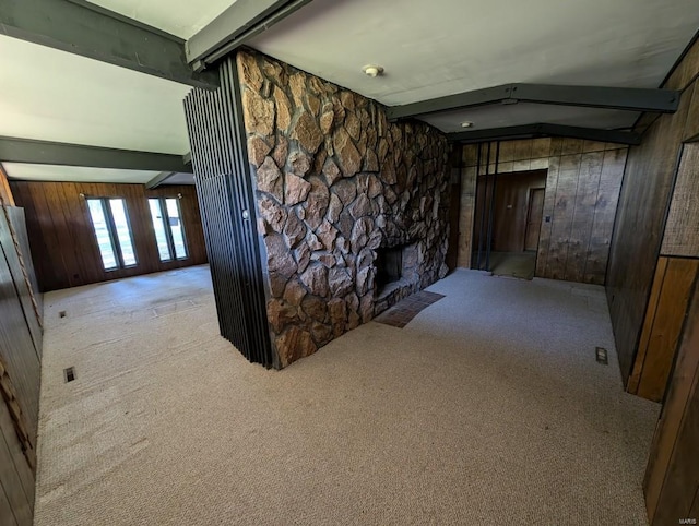 hallway featuring light colored carpet, beam ceiling, and wooden walls