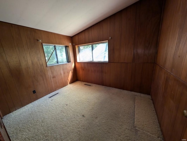 unfurnished room featuring wooden walls, carpet floors, and vaulted ceiling