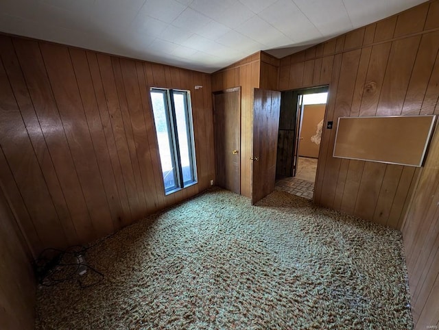 empty room with light colored carpet and wooden walls