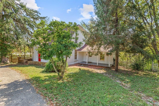 view of property hidden behind natural elements with a front yard and a porch