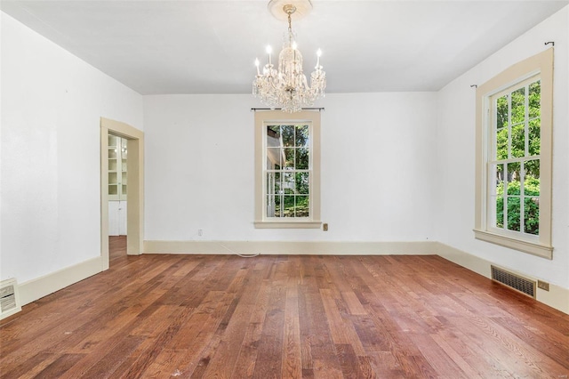 empty room with a chandelier and wood-type flooring