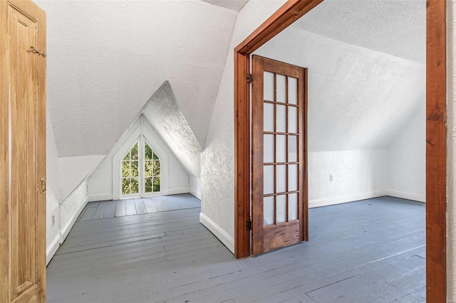 bonus room with lofted ceiling, hardwood / wood-style floors, and a textured ceiling