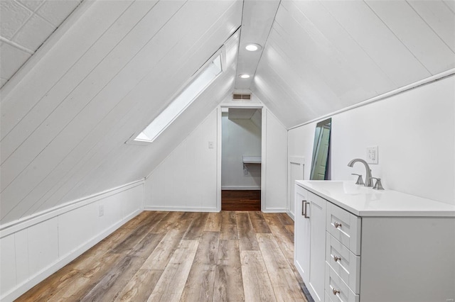 interior space with light hardwood / wood-style floors, sink, and lofted ceiling with skylight