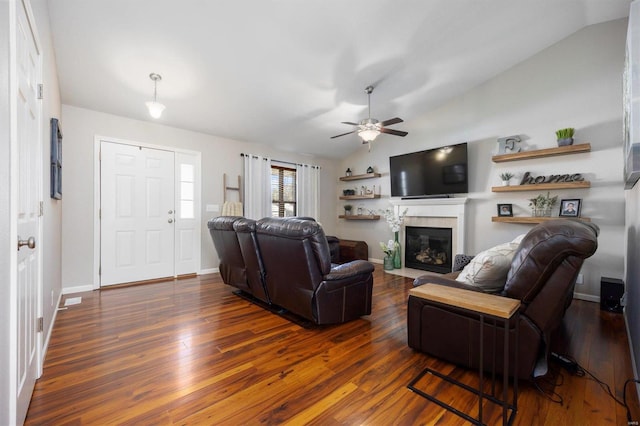 living room featuring ceiling fan, dark wood-type flooring, and vaulted ceiling