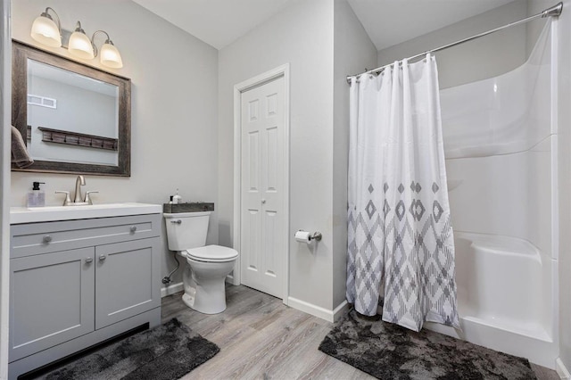 bathroom featuring toilet, walk in shower, hardwood / wood-style flooring, and vanity