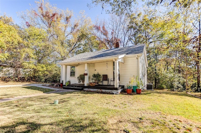 view of front of home with cooling unit, a front lawn, and covered porch