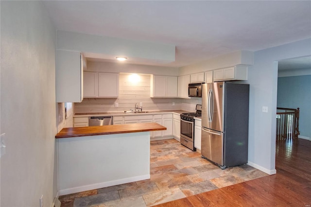 kitchen featuring stainless steel appliances, wood counters, sink, white cabinets, and light hardwood / wood-style floors