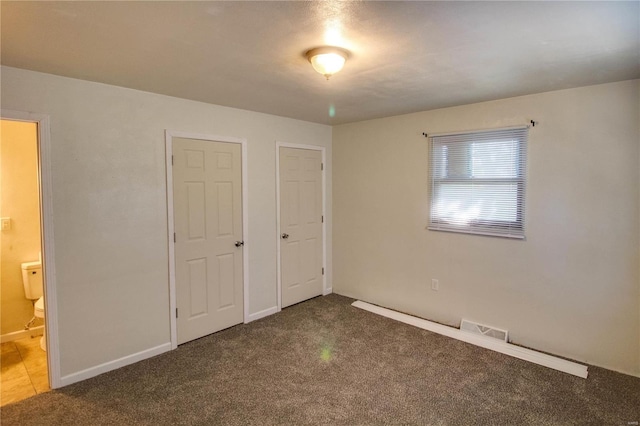 unfurnished bedroom featuring ensuite bathroom and carpet floors