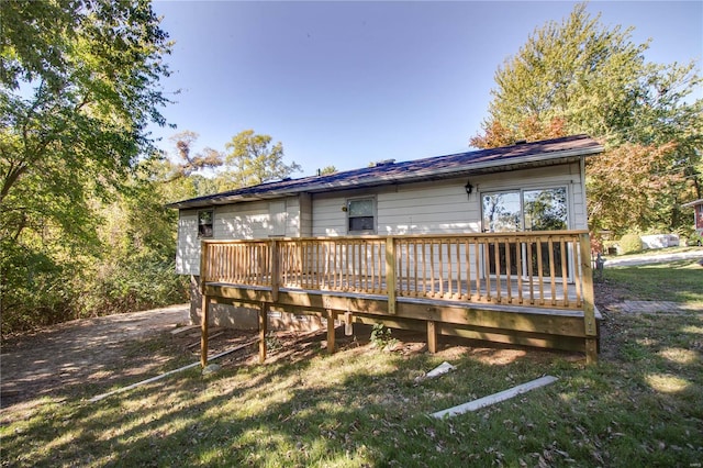 back of property featuring a wooden deck and a yard