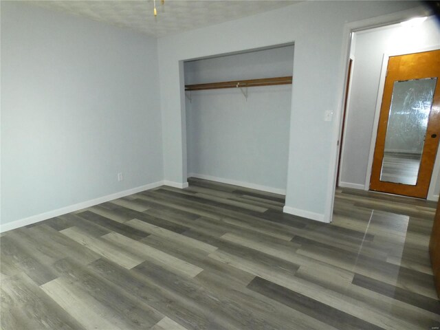 unfurnished bedroom featuring a textured ceiling, a closet, and dark hardwood / wood-style flooring