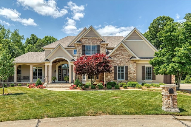 craftsman-style house featuring stone siding, stucco siding, a shingled roof, and a front yard