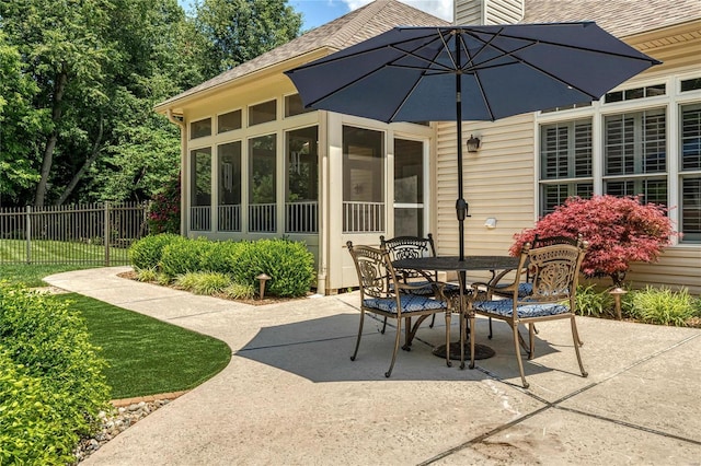 view of patio / terrace featuring fence, outdoor dining area, and a sunroom