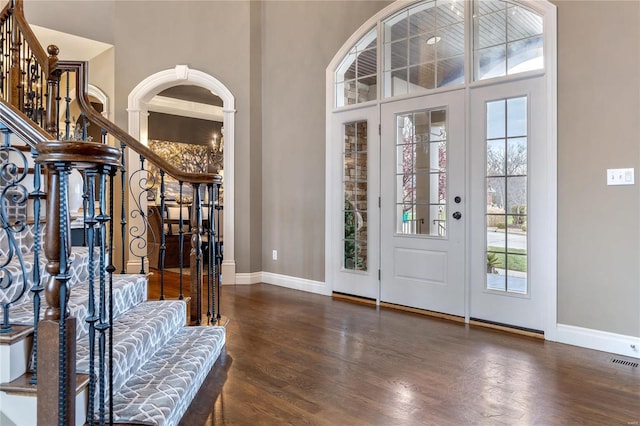 foyer with stairway, wood finished floors, visible vents, baseboards, and a towering ceiling