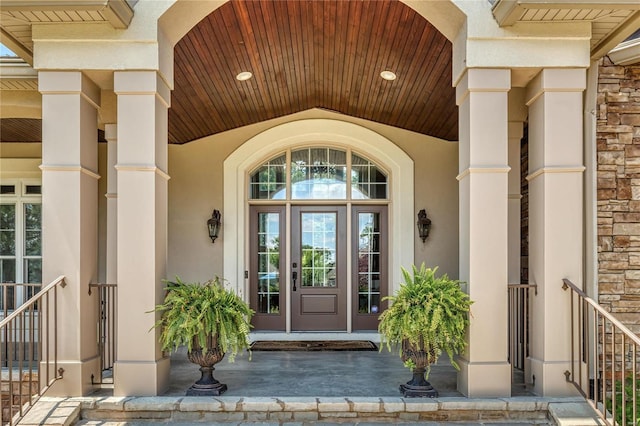 doorway to property with stucco siding, stone siding, and french doors