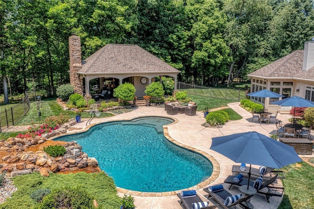 pool featuring a storage structure, a lawn, a fenced backyard, an outbuilding, and a patio