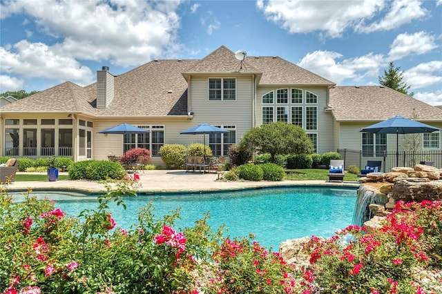 outdoor pool with a patio area, fence, and a sunroom