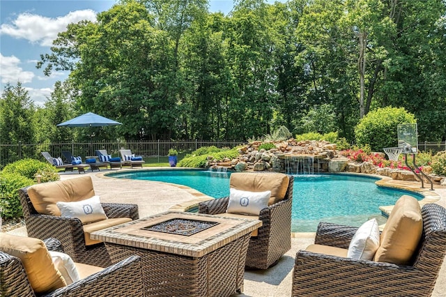 view of swimming pool with an outdoor living space with a fire pit, a patio area, fence, and a fenced in pool