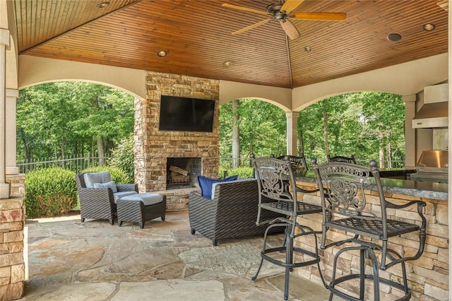 view of patio with a gazebo, an outdoor stone fireplace, an outdoor kitchen, and a ceiling fan