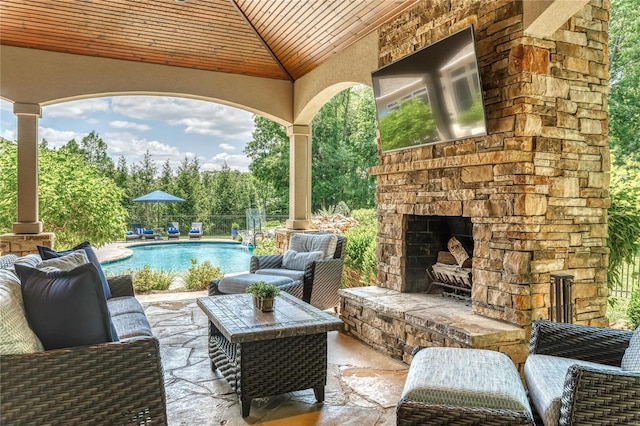 view of patio / terrace featuring an outdoor living space with a fireplace, an outdoor pool, and fence