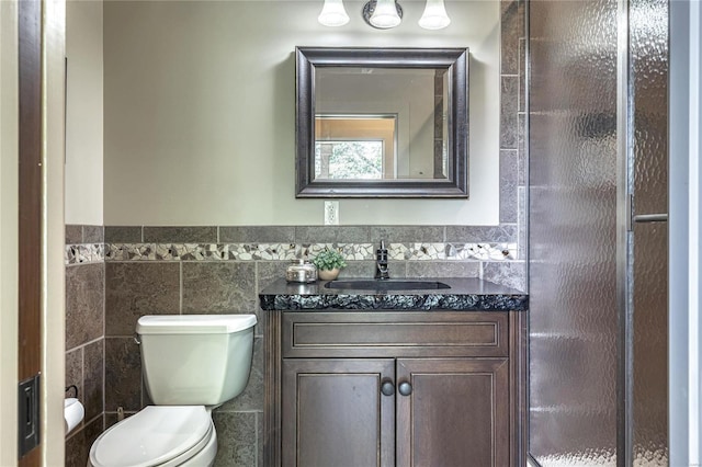 bathroom featuring vanity, tile walls, toilet, and wainscoting