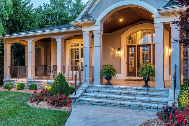 doorway to property with covered porch and stucco siding