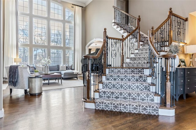 stairs with a high ceiling, a healthy amount of sunlight, and wood finished floors