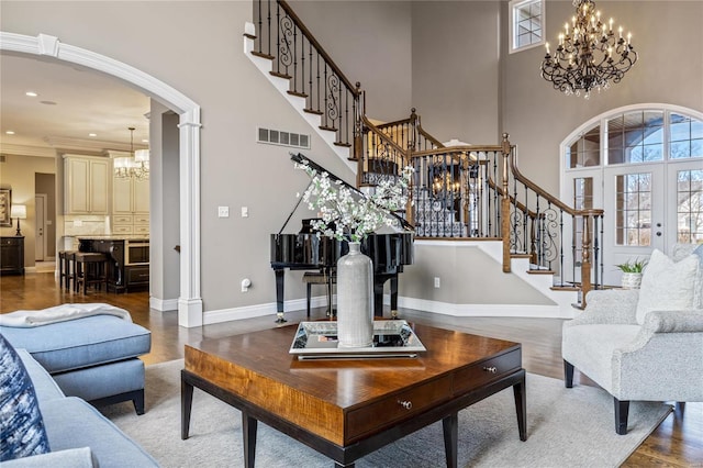 living room with a chandelier, visible vents, arched walkways, and a wealth of natural light