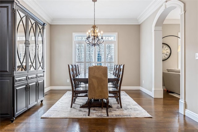 dining space featuring dark wood finished floors, a chandelier, arched walkways, and baseboards