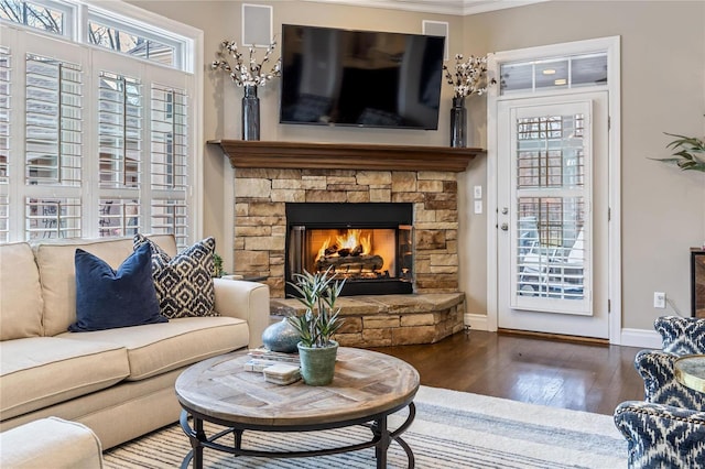 living area featuring baseboards, hardwood / wood-style floors, a fireplace, and crown molding