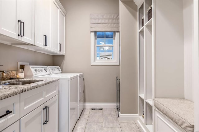 laundry room featuring visible vents, baseboards, cabinet space, a sink, and washer and dryer