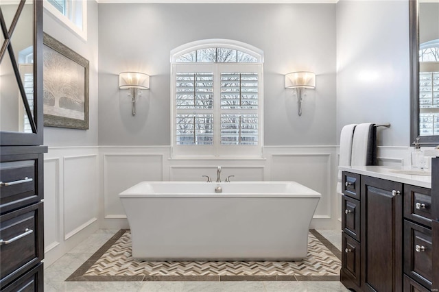 full bath with a freestanding tub, wainscoting, vanity, and a decorative wall