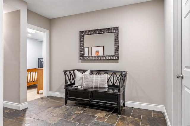 hall with baseboards and stone tile floors