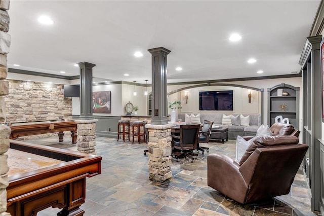 living room featuring recessed lighting, stone finish floor, ornamental molding, and ornate columns