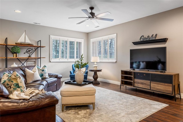 living area with visible vents, wood finished floors, baseboards, and ceiling fan