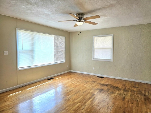 unfurnished room featuring light hardwood / wood-style flooring, a textured ceiling, plenty of natural light, and ceiling fan